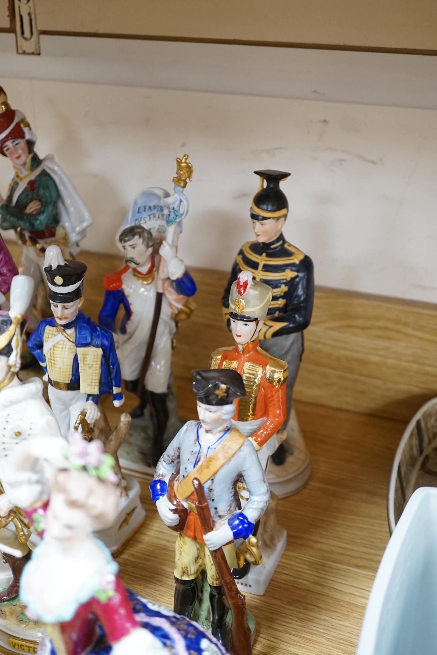 A group of Continental porcelain military figures, two porcelain figures of dancing females and four pieces of tableware in the form of fruit
